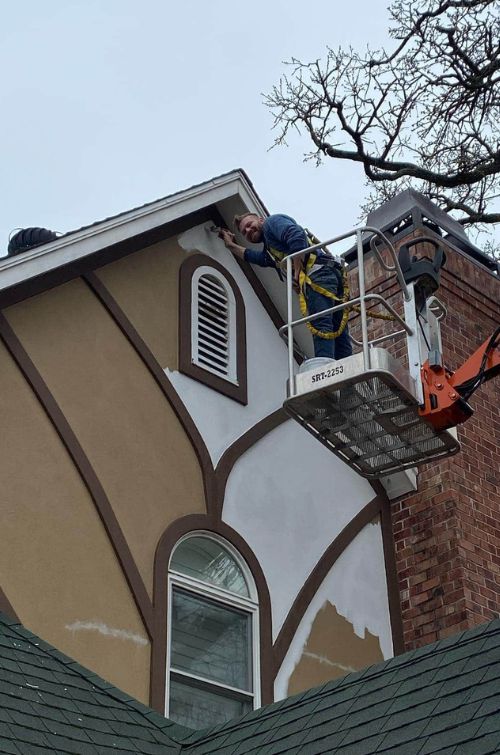 Painter on a lift applying fresh paint to the building’s exterior trim.