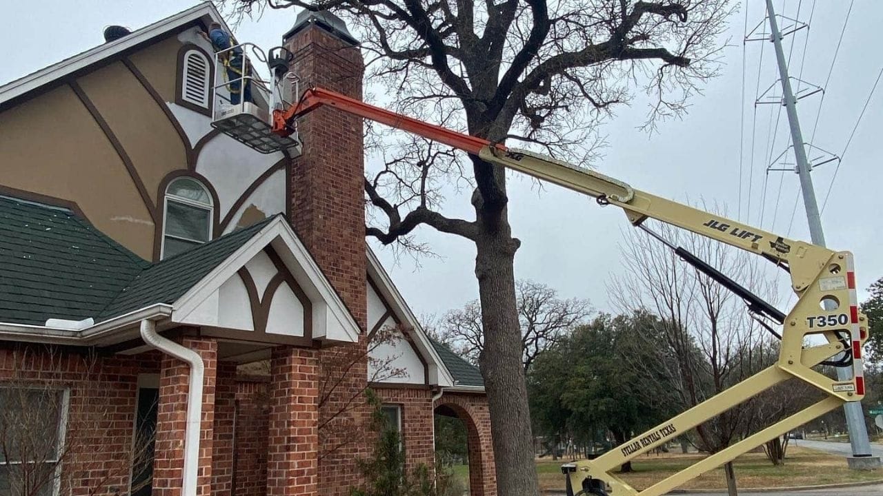 Painters performing exterior house painting using professional lifting equipment.