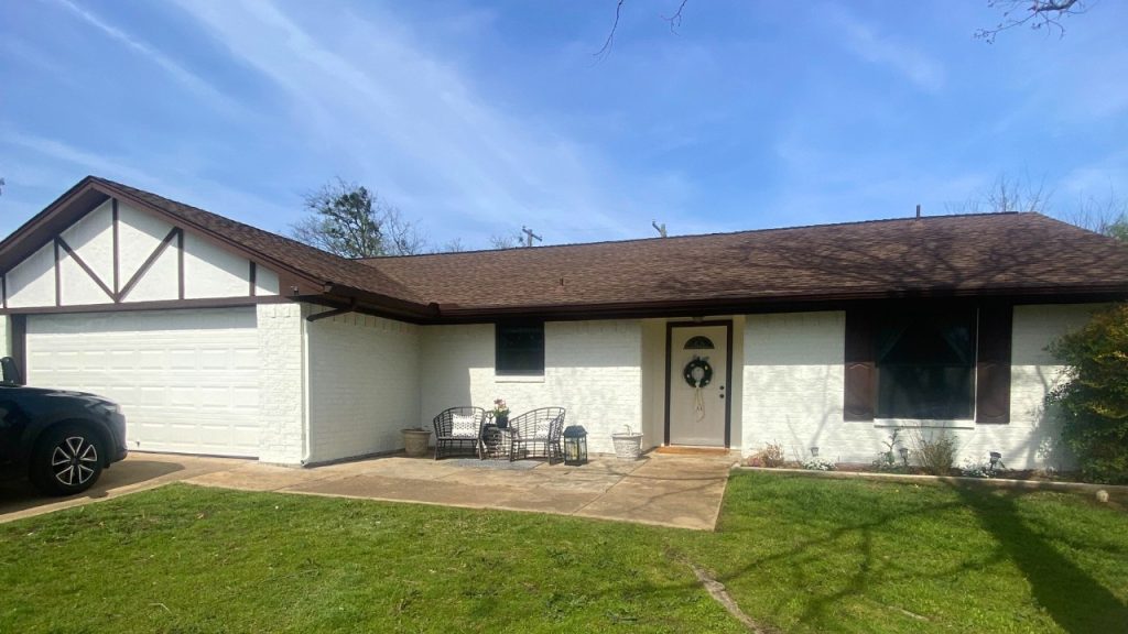 Image of a newly painted brick home with a bright, refreshed exterior replacing its previously dark, weathered look.