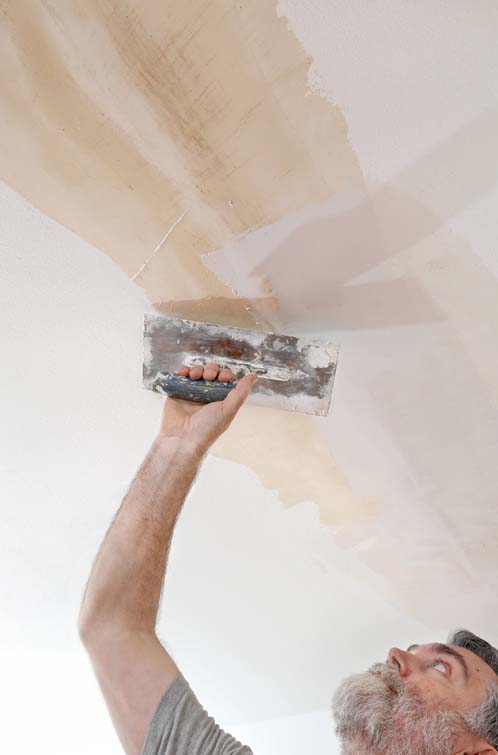 Close-up of the ceiling being repaired after the popcorn texture has been removed.