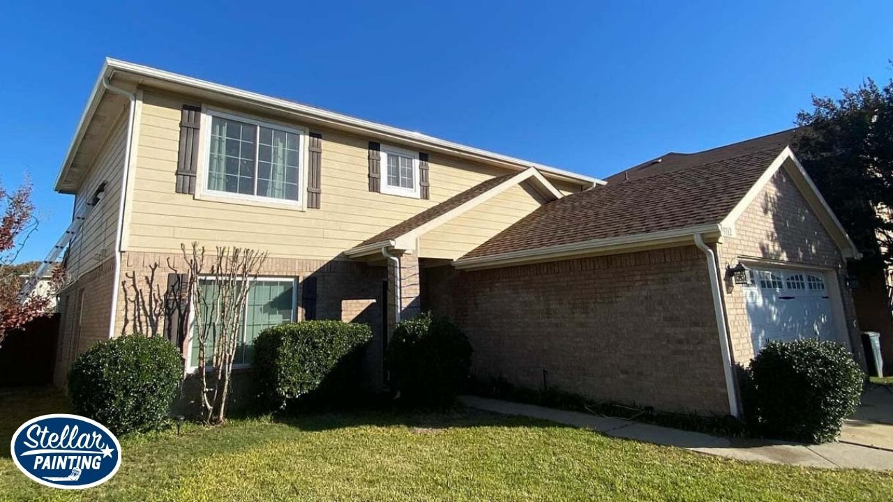 Exterior Painting Alexandra Meadows Fort Worth, TX - Seasonal Adjustments - Stellar Painting This is an exterior painting project by Stellar Painting in Alexandra Meadows Fort Worth, TX, featuring a two-story home with beige siding and brick facade.